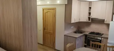 a kitchen with white cabinets and a sink and a door at Gimnazijos apartamentai in Biržai