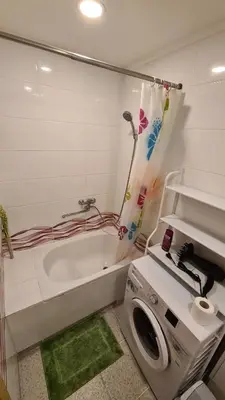 a bathroom with a tub and a washing machine at Gimnazijos apartamentai in Biržai