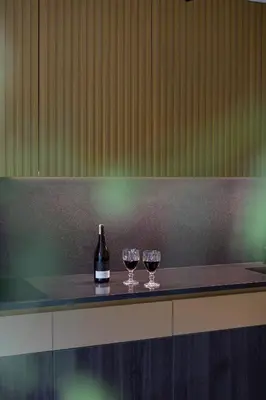two wine glasses and a bottle on a counter at French Park View Apartment in Vilnius