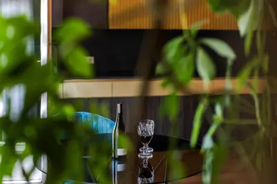 a glass of wine sitting on a glass table at French Park View Apartment in Vilnius
