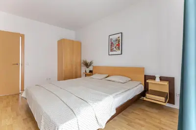 a bedroom with a white bed and a wooden floor at Barbacan by Monto in Vilnius