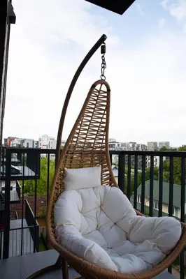 a wicker swing chair on a balcony with a view at Brand new luxurious apartment in Vilnius center in Vilnius