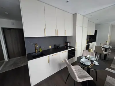 a kitchen with white cabinets and a table and chairs at Brand new luxurious apartment in Vilnius center in Vilnius