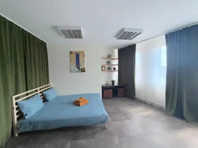 a bedroom with a bed with blue sheets and green curtains at Cozy Seliu 29 in Vilnius