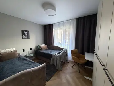 a bedroom with a bed and a chair and a window at Two bedroom LUXURIOUS Spacios Apartment in Vilnius