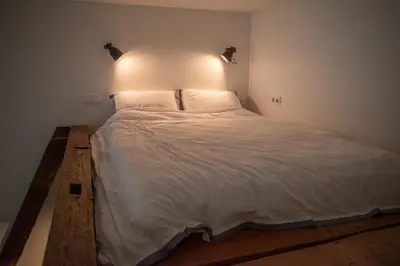 a bedroom with a large white bed with lights on it at Steponas Old Town Studio in Vilnius