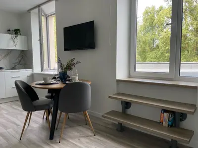a dining room with a table and chairs and a tv at Apartment Parko in Molėtai