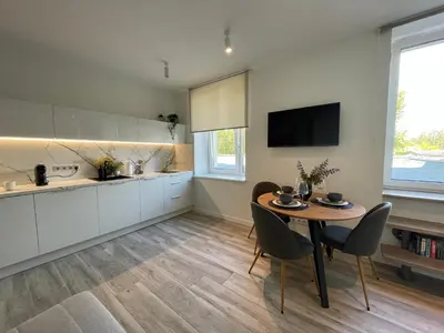 a kitchen with a table and chairs and a television at Apartment Parko in Molėtai
