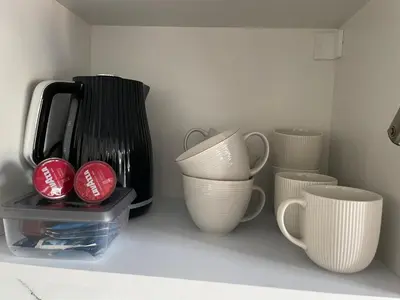 a shelf with white cups and a black appliance at Apartment Parko in Molėtai