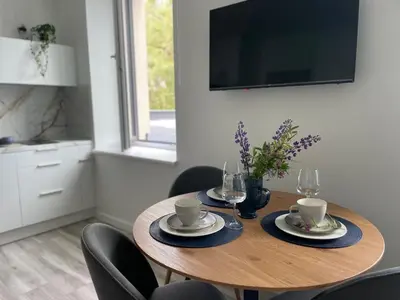 a dining room table with chairs and a television at Apartment Parko in Molėtai