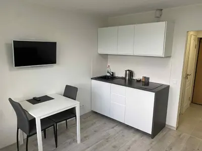 a kitchen with a table and a white table and chairs at VILNIUS apartment with balcony in Vilnius