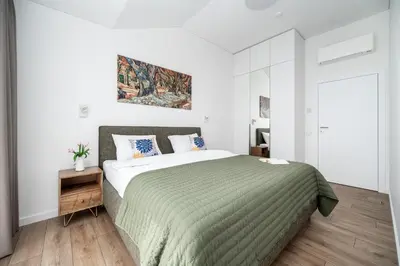 a bedroom with a large bed with a green blanket at Top Floor, Spacious Apartment w-Balcony & Garage I Cohost in Vilnius