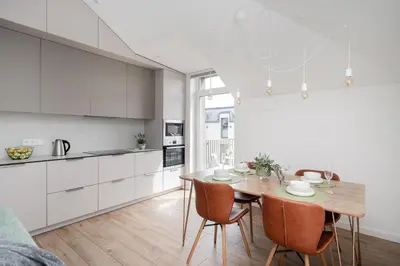 a kitchen and dining room with a wooden table and chairs at Top Floor, Spacious Apartment w-Balcony & Garage I Cohost in Vilnius