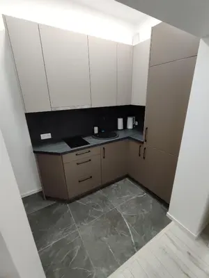 a small kitchen with white cabinets and a tile floor at UrbanHome Rokiškis in Rokiškis
