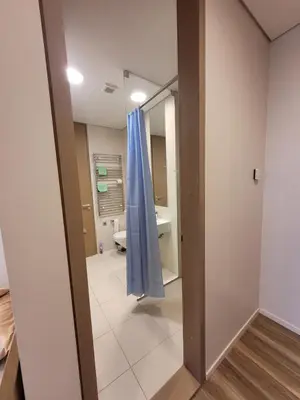 a bathroom with a blue curtain in a room at Šiluvos piligrimų centras in Šiluva