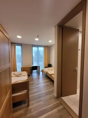 a room with two beds and a door to a bedroom at Šiluvos piligrimų centras in Šiluva