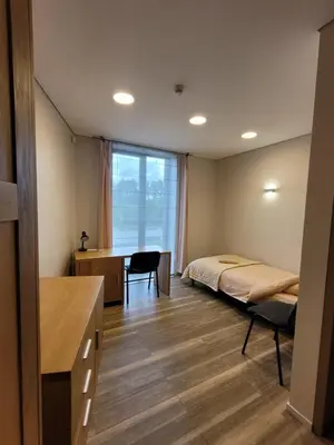 a bedroom with a bed and a desk and a table at Šiluvos piligrimų centras in Šiluva