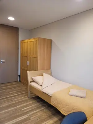 a bedroom with a bed and a wooden cabinet at Šiluvos piligrimų centras in Šiluva