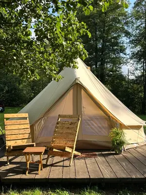 a tent with two chairs and a table on a wooden deck at Glamp Juodis in Ubiškės