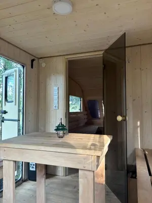 a wooden table in the front of a tiny house at Glamp Juodis in Ubiškės