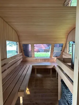 a room with benches and windows in a tiny house at Glamp Juodis in Ubiškės