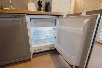 an empty refrigerator with its door open in a kitchen at Vakaris in Pabradė