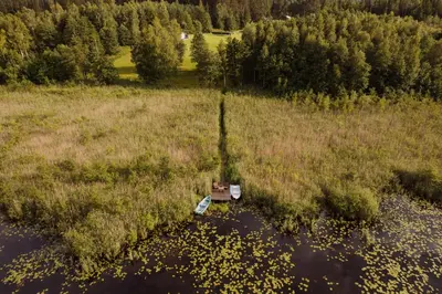 an aerial view of a field with a boat in the water at Vakaris in Pabradė