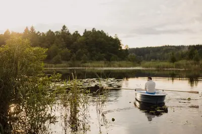 a man is sitting in a boat on a lake at Vakaris in Pabradė