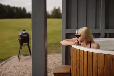 a woman sitting in a bath tub with a glass of wine at Vakaris in Pabradė