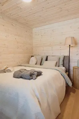 a large bed in a room with wooden walls at Vakaris in Pabradė