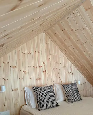 a bed in a room with a wooden wall at Miško Kortai