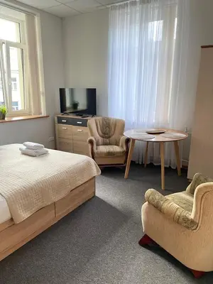 a bedroom with a bed and a table and a chair at Studija Mona in Vilnius