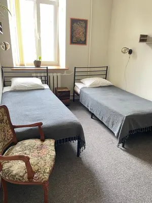 a bedroom with two beds and a chair and a window at Studija Mona in Vilnius