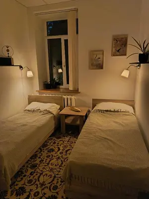 a bedroom with two beds and a window and a table at Studija Mona in Vilnius