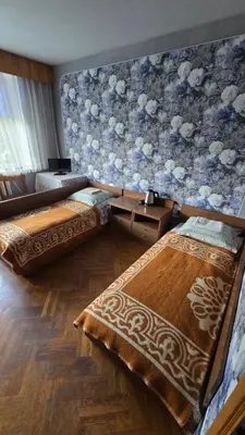 a room with two beds and a wall with flowers at Pas Povilą in Jurbarkas