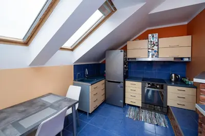 a kitchen with a table and a refrigerator in a attic at Spacious & Private Stay in Garliava 120kv in Garliava