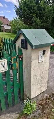 a green and white out house next to a gate at Spacious & Private Stay in Garliava 120kv in Garliava