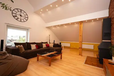 a living room with a couch and a clock on the wall at Spacious & Private Stay in Garliava 120kv in Garliava