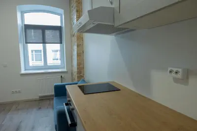 a room with a wooden table and a kitchen at Tiny Brick Loft in Vilnius
