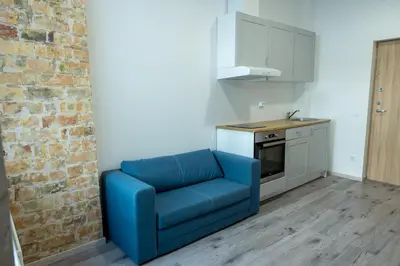 a blue chair in a kitchen with a brick wall at Tiny Brick Loft in Vilnius