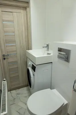 a white bathroom with a toilet and a sink at Tiny Brick Loft in Vilnius