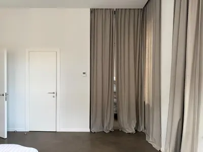 a bedroom with white walls and white curtains at Nemunas Apartaments in Kaunas