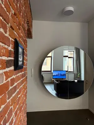 a circular mirror on a wall next to a brick wall at Nemunas Apartaments in Kaunas