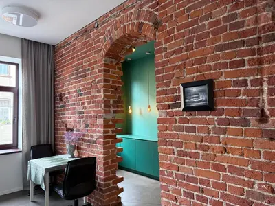 a brick wall in a room with a table and a chair at Nemunas Apartaments in Kaunas