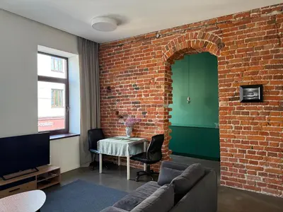 a living room with a couch and a brick wall at Nemunas Apartaments in Kaunas