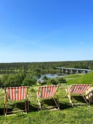 two chairs sitting in the grass next to a river at Sapnų cechas in Merkinė
