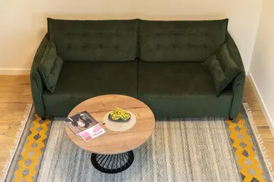 a living room with a green couch with a table at Sapnų cechas in Merkinė