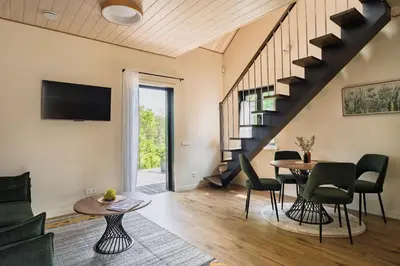 a living room with a table and chairs and a staircase at Sapnų cechas in Merkinė