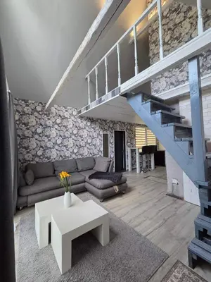 a living room with a couch and a staircase at Sodyba Upulupu