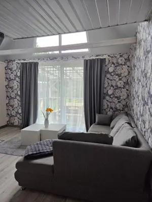 a living room with a couch and a large window at Sodyba Upulupu